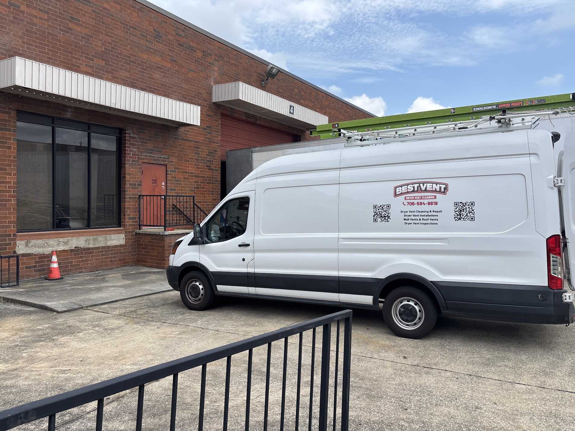 White Best Vent service van with a green ladder parked outside a red brick building.