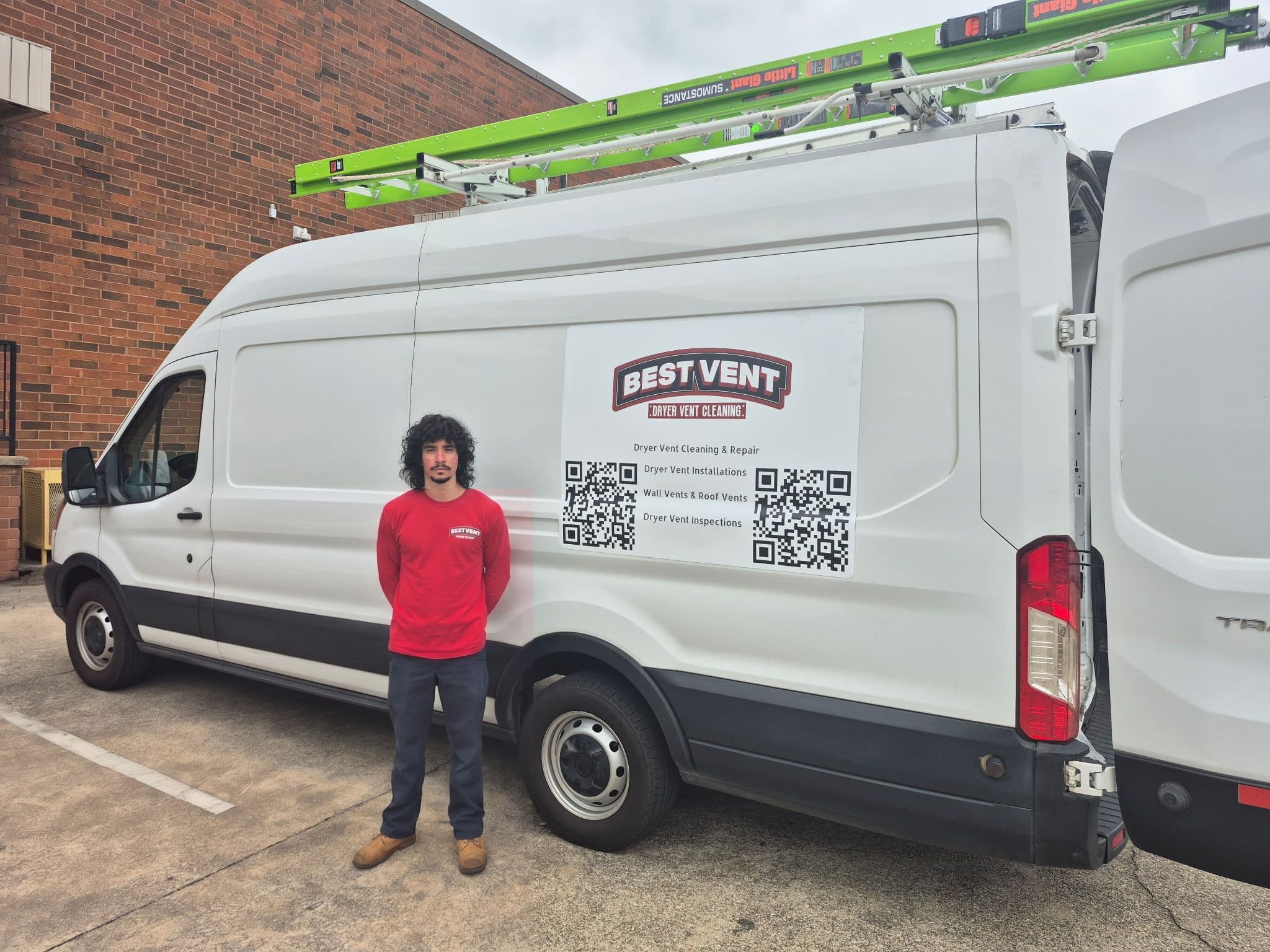 Technician in red shirt stands beside a white Best Vent service van with roof ladders.